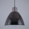 Pendant light with dark glass shade and metallic fixture on a gray background
