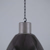 Black pendant light with metallic fixture against a gray background