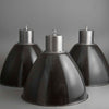 Three black industrial-style pendant lights on a gray background