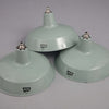 Three 1950s mint green enamel industrial pendant light by REVO on a grey background.