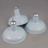 Three Vintage industrial pale blue enamel pendant lights made in England 1950-1960in front of grey background