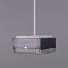 A retro square glass pendant light. 260mm square prismatic glass shades with a black metal housing ceiling mounted on a white rod.