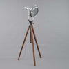 A tall tripod floor lamp comprising a cast aluminium flood light by GEC fitted to a WW2 telescopic hardwood tripod