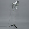 Mid century industrial floor lamp with large metal shade on a gray background