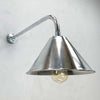 an industrial style aluminium wall light. It has a conical shaped aluminium lamp shade which is attached to a curved galvanised steel wall arm making this a wall mounted down light ideal for illuminating pictures on the wall or adding ambience alongside ceiling lights.