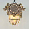 An industrial bronze ceiling light with a brass cage covering a tempered glass dome reclaimed from old ships and restored for modern interiors. Worldwide shipping is available. 15 of these fixtures are available for sale.
