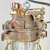 An industrial bronze ceiling light with a brass cage covering a tempered glass dome reclaimed from old ships and restored for modern interiors. Worldwide shipping is available. 15 of these fixtures are available for sale.