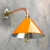 An orange cantilever light with copper and brass wall fixture. The orange lamp shade is based on the design of the British military festoon shades. Colourful industrial style wall lights for contemporary interiors.