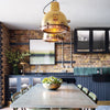 Original industrial brass hanging lights over dining table in an industrial style loft apartment kitchen diner.