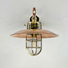 The copper& brass wall light is a reclaimed vintage industrial explosion proof brass lamp. Full of industrial style with a protective brass cage, copper shade and copper wall arm this wall lamp is beautifully restored for modern interiors. The light fixture extends out from the wall on a copper cantilever arm fixture.