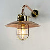 The copper& brass wall light is a reclaimed vintage industrial explosion proof brass lamp. Full of industrial style with a protective brass cage, copper shade and copper wall arm this wall lamp is beautifully restored for modern interiors. The light fixture extends out from the wall on a copper cantilever arm fixture.