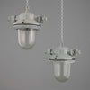 Two industrial pendant lights hanging against a gray background