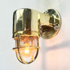 Shop for a small brass nautical wall light. Reclaimed from old ships and restored. This small vintage wall light features a brass cage and tempered glass which covers and protects the lamp holder. Can be used both as small indoor lighting or small outdoor lighting