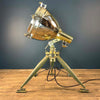 Shop for an industrial floor lamp. Comprised of a vintage aluminium searchlight which has been expertly modified to integrate seamlessly with the USA military tripod made in 1986 by Fortners Machine Shop, secured by three brass thumb screw for stability and functionality. A cast brass Wiska rotary marine isolator switch provides a reliable and straightforward mechanism for operating the lamp.