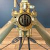 Shop for a steampunk style floor lamp. Comprised of a searchlight which has been expertly modified to integrate seamlessly with the tripod, secured by three brass thumb screws for stability and functionality. A cast brass Wiska rotary marine isolator switch provides a reliable and straightforward mechanism for operating the lamp.