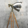 A vintage industrial floor lamp in stainless steel and brass. The steel Searchlight is paired with a timber and bronze tripod to create a unique bespoke floor lamp.