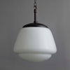 White opaline glass pendant light with a dark brown Bakelite fixture on a gray background