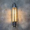 A vintage industrial caged wall strip light restored with T8 LED tubes mounted vertically on a concrete wall.