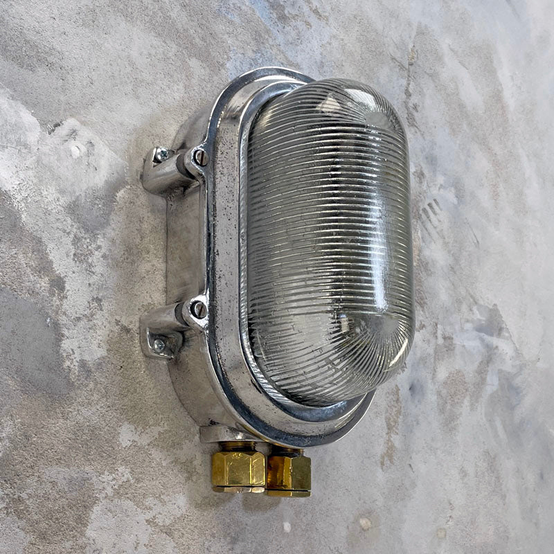 Aluminium bulkhead light for modern interiors. Our industrial wall sconce is rewired compatible with LED light bulbs. With a prismatic glass cover which softens the illumination