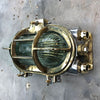 A vintage industrial brass and aluminium tilting wall bulkhead wall light with prismatic glass.