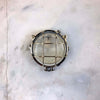a vintage brass circular bulkhead wall light with prismatic glass shade and industrial cage