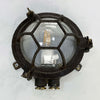 Black iron wall light with cage and prismatic glass cover. The round bulkhead is reclaimed and restored for modern interiors compatible with LED light bulb.