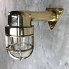 A reclaimed retro industrial solid brass 90 degree outdoor wall light with protective cage.