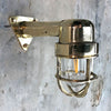 A reclaimed retro industrial solid brass 90 degree outdoor wall light with protective cage.