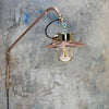 A vintage industrial style copper swing arm wall light with brass explosion proof pendant light.