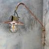 A vintage industrial style copper swing arm wall light with brass explosion proof pendant light.