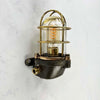 This robust industrial cage wall light manufactured C1995, comprises a cast steel main body, a tempered glass dome with a protective brass and bronze cage.