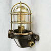 This robust industrial cage wall light manufactured C1995, comprises a cast steel main body, a tempered glass dome with a protective brass and bronze cage.