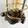 This robust industrial cage wall light manufactured C1995, comprises a cast steel main body, a tempered glass dome with a protective brass and bronze cage.
