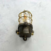 This robust industrial cage wall light manufactured C1995, comprises a cast steel main body, a tempered glass dome with a protective brass and bronze cage.