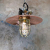 A reclaimed vintage industrial explosion proof copper ceiling pendant light with a protective brass cage.