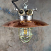 A reclaimed vintage industrial explosion proof copper ceiling pendant light with a protective brass cage.