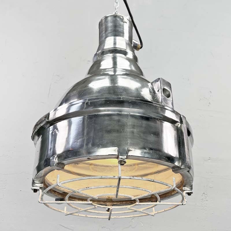 The large explosion proof cast aluminium pendant light was made by the Indian company Baliga Lighting Equipments Ltd. It is a very heavy solid metal light fixture which features a cage over the tempered glass lens that protects the lamp holder from external elements.&nbsp;