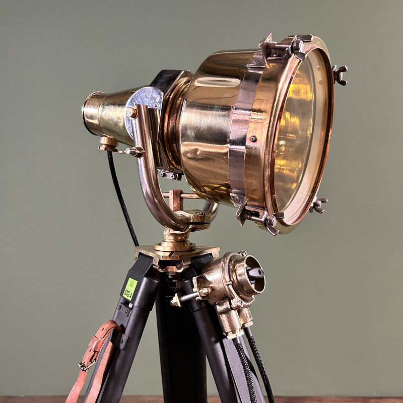brass tripod floor lamp. A reclaimed brass searchlight paired with a wooden tripod which has been painted black and a switch mounted to the tripod. 
