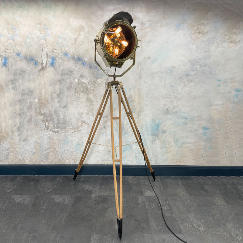 A tall nautical brass and steel searchlight mounted onto a British antique wooden surveyors tripod. A unique and original tall tripod floor lamp perfect for creating the "wow" factor with a nautical style fixture.