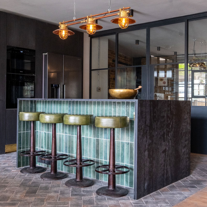 industrial style copper & brass 3 pendant ceiling light on a copper bar hanging over an industrial style kitchen diner