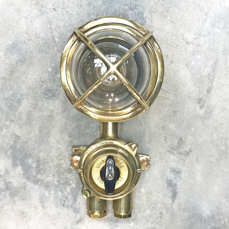 Outdoor explosion proof brass wall light with switch. Restored lighting with protective cage