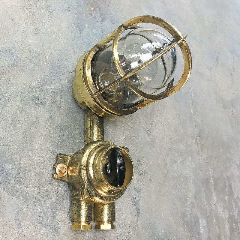 Outdoor explosion proof brass wall light with switch. Restored lighting with protective cage