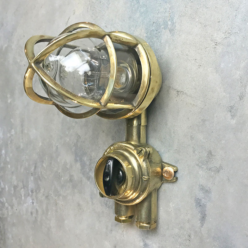 Outdoor explosion proof brass wall light with switch. Restored lighting with protective cage