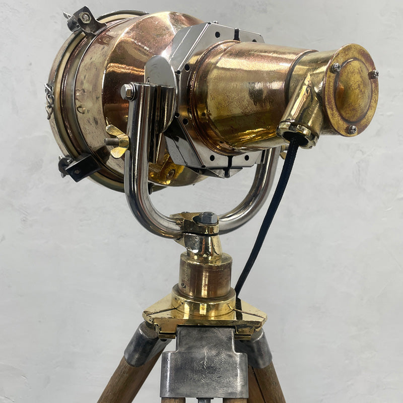 Brass searchlight floor lamp. Reclaimed and restored brass searchlight paired with a wooden tripod and has a floor switch