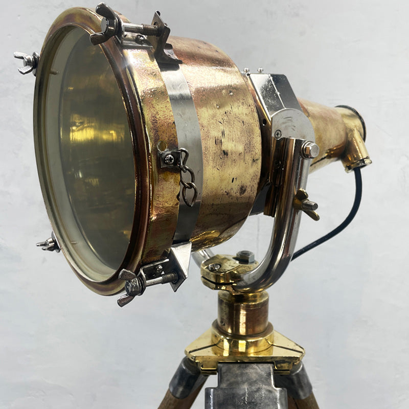 Brass searchlight floor lamp. Reclaimed and restored brass searchlight paired with a wooden tripod and has a floor switch