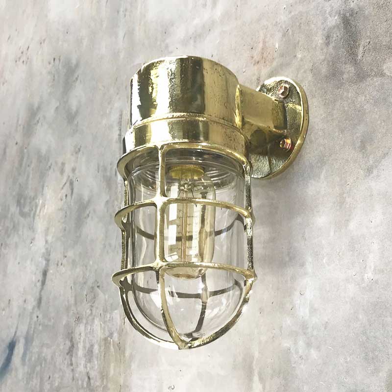 Shop our vintage brass wall sconce. A 90 degree lamp with cast brass cage and tempered glass cover. Industrial lighting reclaimed and restored for modern interiors. This wall lamp can be used outdoors. It is compatible with an LED light bulb. Manufactured by Daeyang a Korean company who made fixtures for industrial purposes.