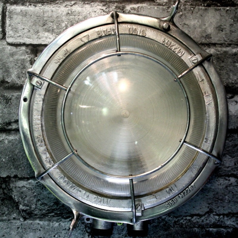 A retro industrial caged aluminium bulkhead wall light with frosted glass and protective cage.
