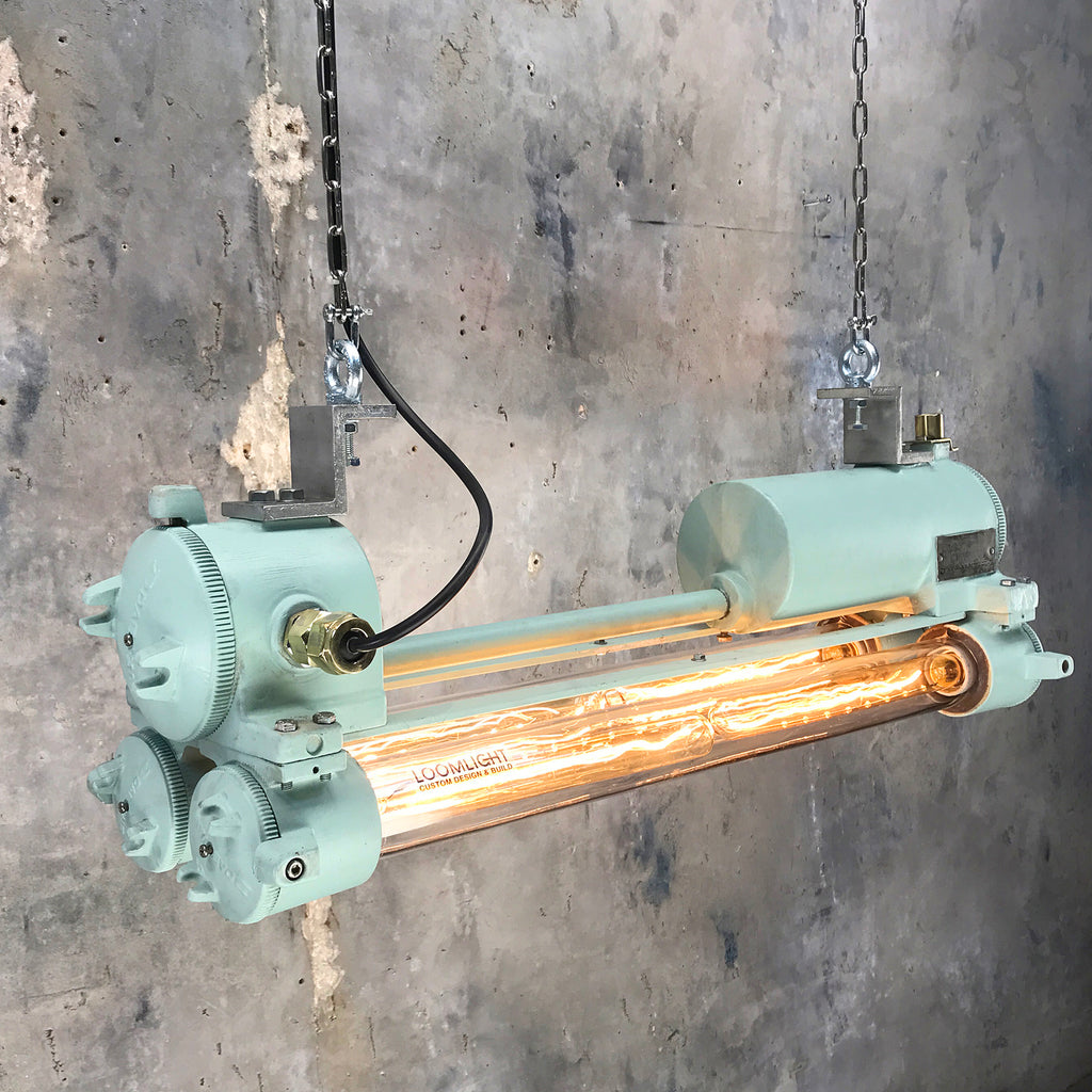 Industrial style vintage strip light painted duck egg green fitted with Edison tubes hanging from a ceiling.