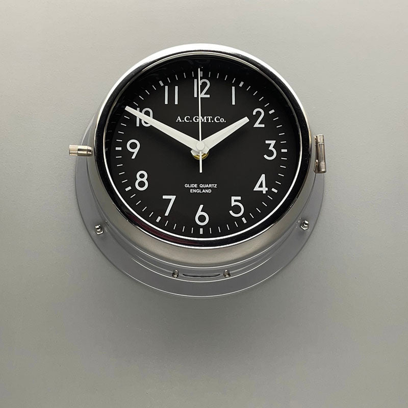 Silver wall clock with black face and white digits. This original nautical wall clock features a quartz silent sweep seconds hand movement meaning no ticking! a timeless and silent wall clock suitable for any contemporary interior.