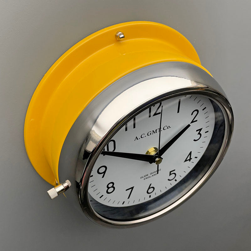 A non-ticking yellow circular wall clock with white face, reclaimed and restored by AC.GMT.Co. 